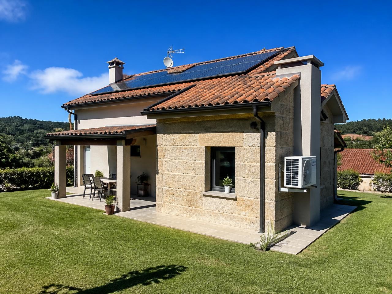 Vivienda con placas solares en el tejado y unidad exterior de aerotermia